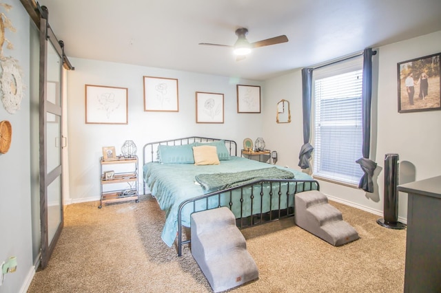 carpeted bedroom featuring a barn door and ceiling fan