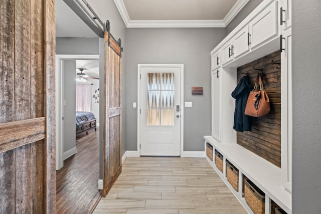 mudroom featuring ornamental molding, a barn door, and light wood-type flooring