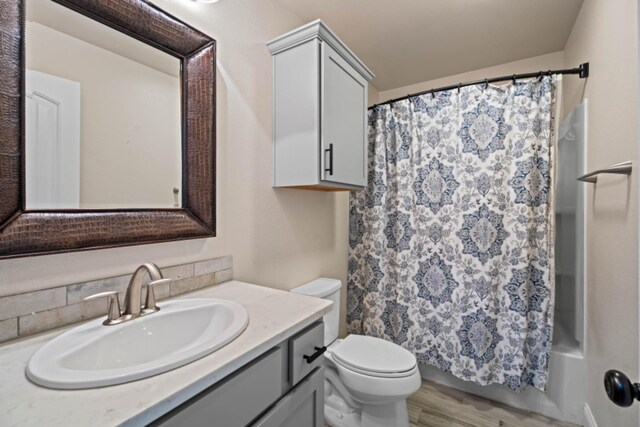 full bathroom featuring vanity, wood-type flooring, shower / bath combo with shower curtain, and toilet