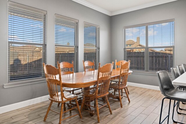 dining space with ornamental molding and light hardwood / wood-style flooring