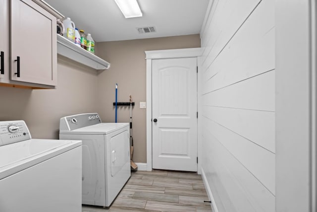 laundry area with cabinets, washer and clothes dryer, and light hardwood / wood-style floors