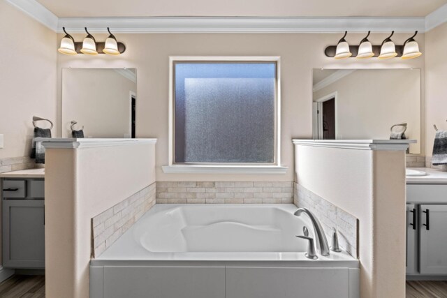 bathroom featuring ornamental molding, vanity, tiled bath, and hardwood / wood-style floors