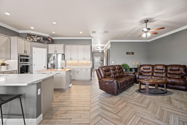 kitchen with tasteful backsplash, white cabinetry, ornamental molding, a center island, and stainless steel appliances