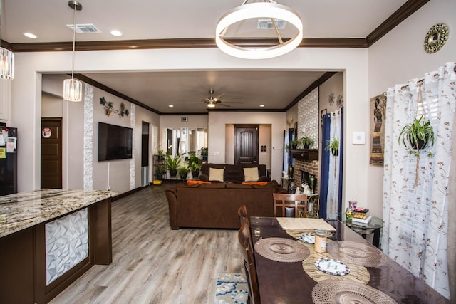 dining room with crown molding, ceiling fan, and light wood-type flooring