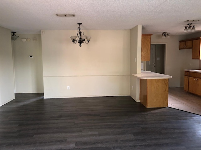 interior space featuring a textured ceiling, a notable chandelier, dark hardwood / wood-style flooring, and decorative light fixtures