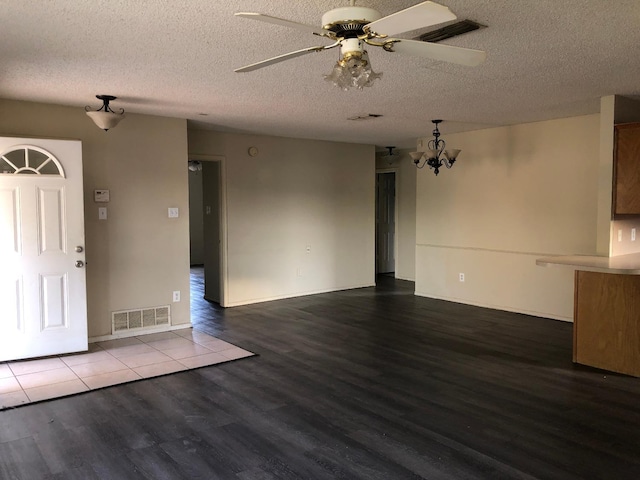 foyer entrance featuring hardwood / wood-style floors, ceiling fan with notable chandelier, and a textured ceiling