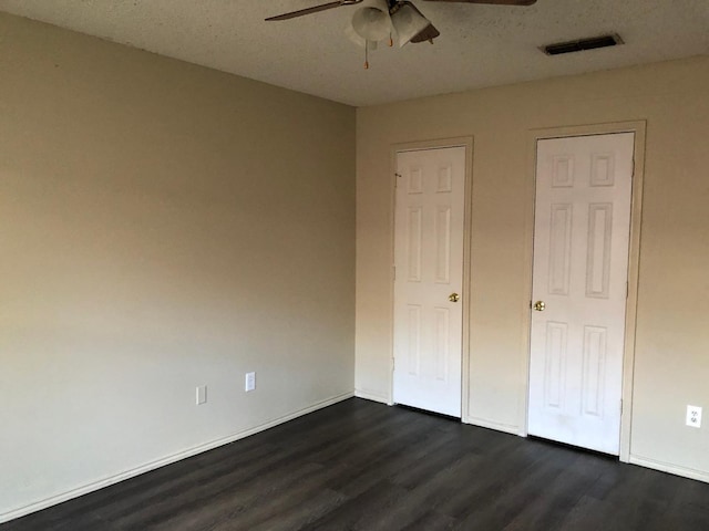 unfurnished bedroom with dark hardwood / wood-style flooring, a textured ceiling, and ceiling fan