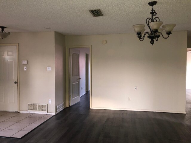 spare room with hardwood / wood-style flooring, an inviting chandelier, and a textured ceiling