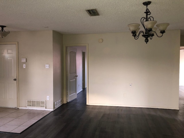 empty room with hardwood / wood-style floors, a notable chandelier, and a textured ceiling