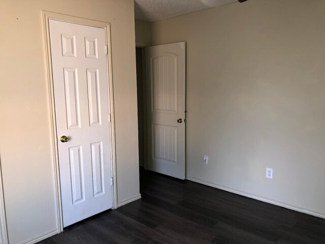 unfurnished bedroom with dark hardwood / wood-style flooring and a textured ceiling