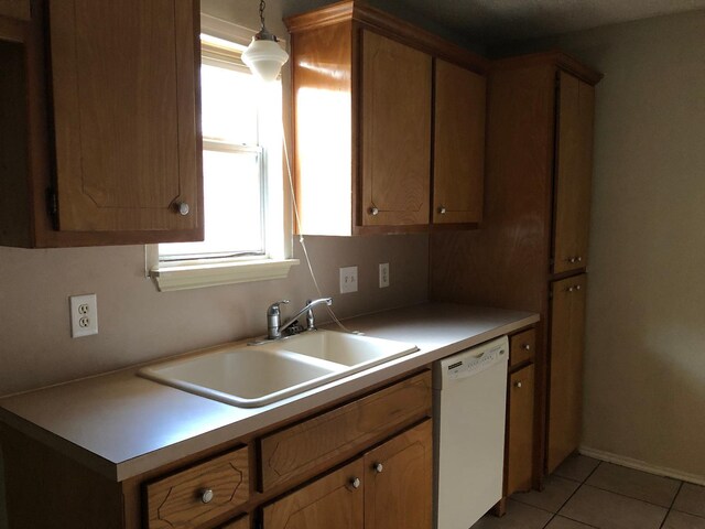 kitchen featuring decorative light fixtures, dishwasher, sink, and light tile patterned floors