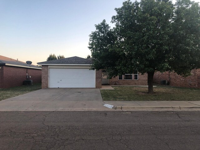 view of front of home featuring a garage, central AC, and a lawn