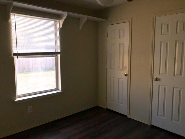 unfurnished bedroom featuring multiple windows and dark hardwood / wood-style flooring