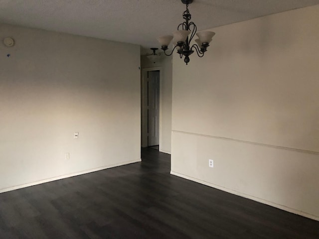 unfurnished room featuring dark hardwood / wood-style floors and a notable chandelier