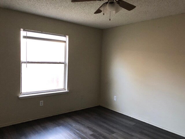 empty room with ceiling fan, dark hardwood / wood-style flooring, and a textured ceiling