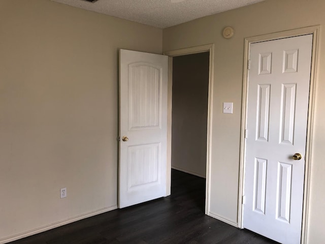 unfurnished bedroom with dark hardwood / wood-style floors and a textured ceiling