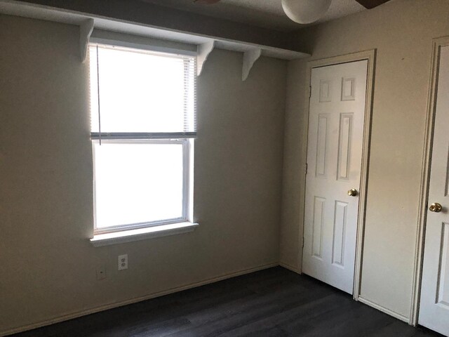 unfurnished bedroom featuring multiple windows and dark hardwood / wood-style flooring