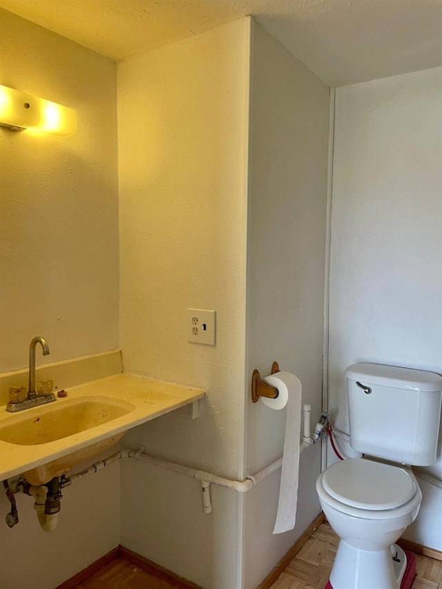 bathroom featuring sink, parquet flooring, and toilet