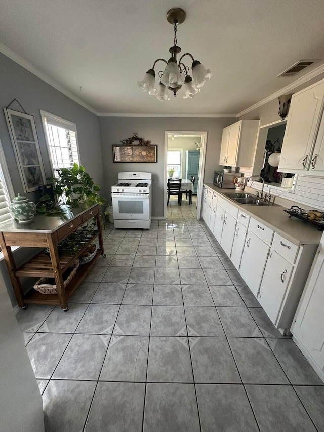 kitchen with sink, white gas stove, white cabinetry, ornamental molding, and pendant lighting