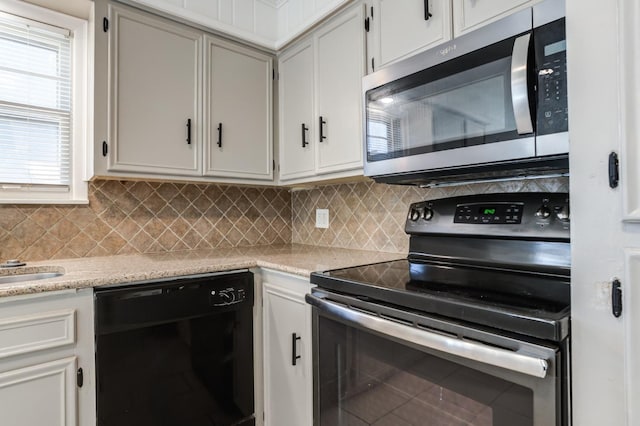 kitchen featuring white cabinetry, stainless steel appliances, light stone counters, and tasteful backsplash