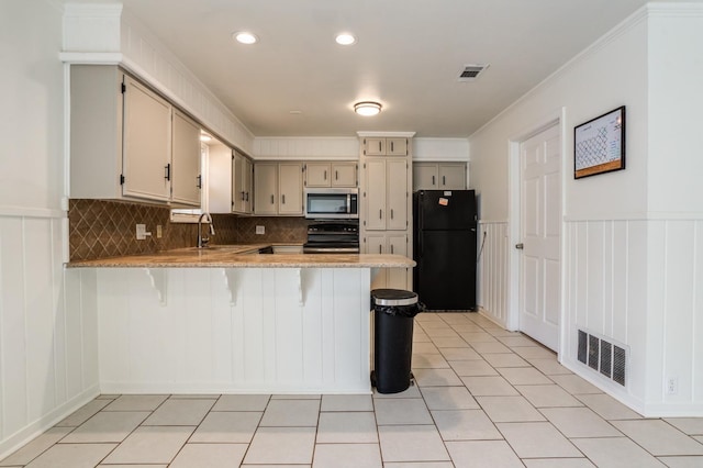 kitchen with range with electric cooktop, black refrigerator, a breakfast bar area, kitchen peninsula, and cream cabinetry