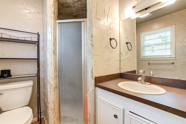 bathroom featuring vanity, a shower with shower door, and toilet