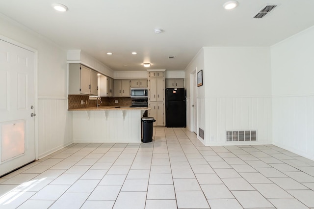 kitchen with light tile patterned flooring, sink, range, black refrigerator, and kitchen peninsula