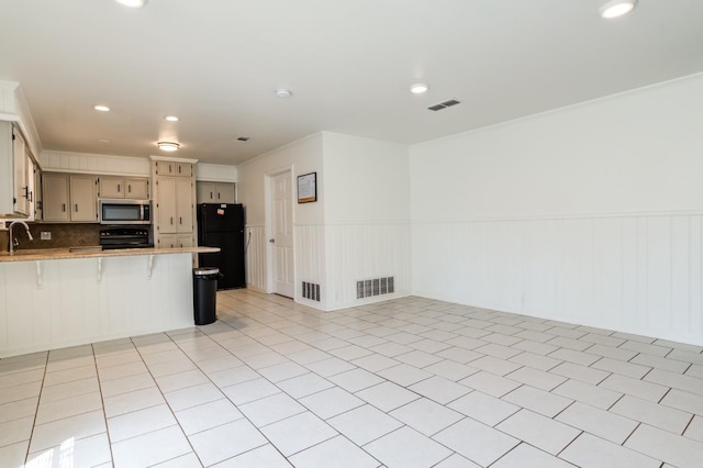 kitchen featuring a breakfast bar area, ornamental molding, range, kitchen peninsula, and black fridge