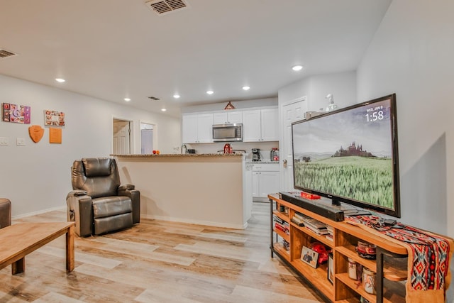 interior space with white cabinets, light stone counters, and light hardwood / wood-style flooring