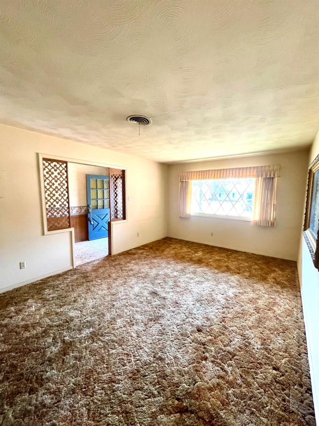 unfurnished room with a textured ceiling and carpet