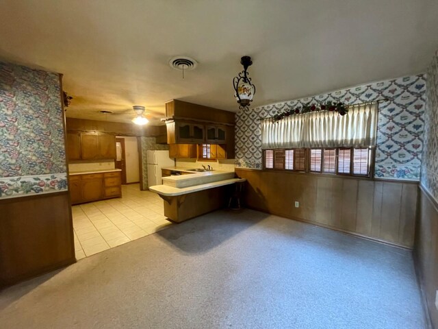 kitchen with decorative light fixtures, sink, white refrigerator, light tile patterned floors, and kitchen peninsula