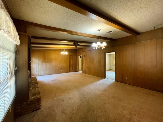 unfurnished room with carpet flooring, beam ceiling, a textured ceiling, and wood walls