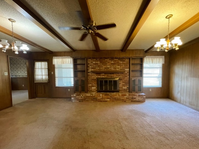 unfurnished living room with wooden walls, beam ceiling, a textured ceiling, and a fireplace