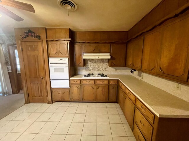 kitchen featuring backsplash, white appliances, light tile patterned floors, and ceiling fan