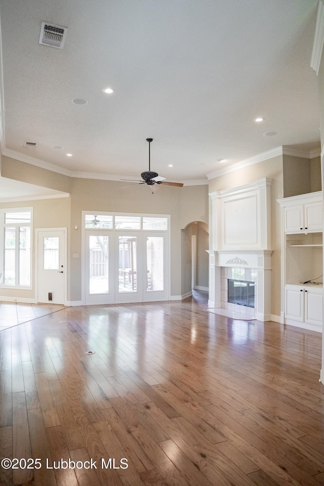 9805 Savannah Ave, Lubbock, TX 79424 - unfurnished living room featuring a ceiling fan, arched walkways, a tile fireplace, baseboards, and ornamental molding