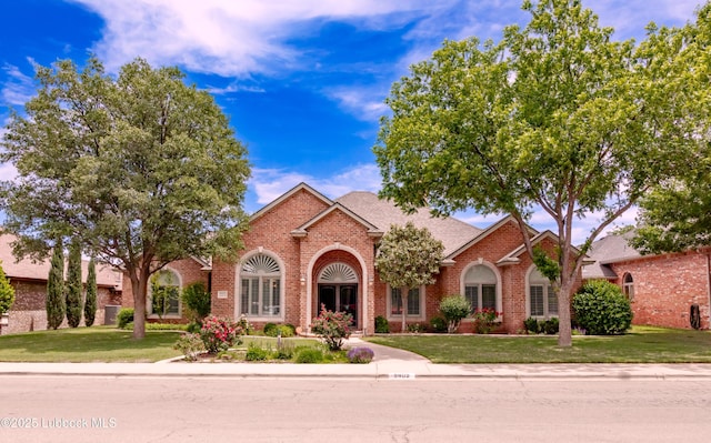 9805 Savannah Ave, Lubbock, TX 79424 - traditional home featuring brick siding, a front yard, and a shingled roof
