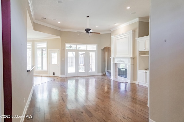 9805 Savannah Ave, Lubbock, TX 79424 - unfurnished living room featuring a ceiling fan, light wood-style floors, arched walkways, a tiled fireplace, and recessed lighting
