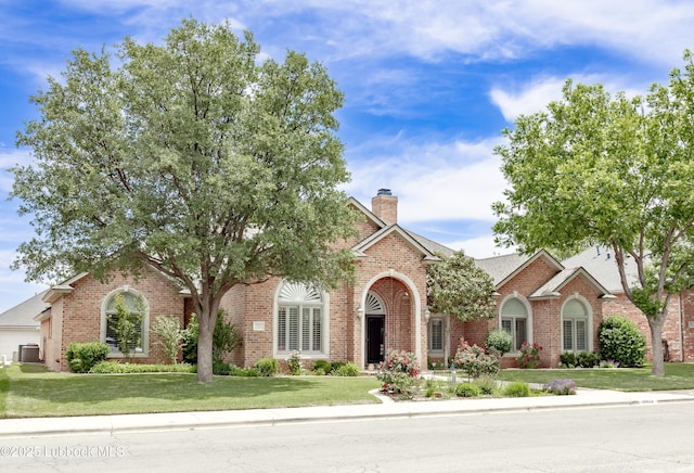 9805 Savannah Ave, Lubbock, TX 79424 - view of front of home with brick siding, cooling unit, a front lawn, and a chimney