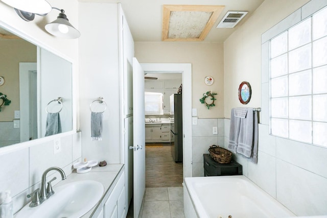 bathroom with vanity, tile patterned flooring, tile walls, and a tub