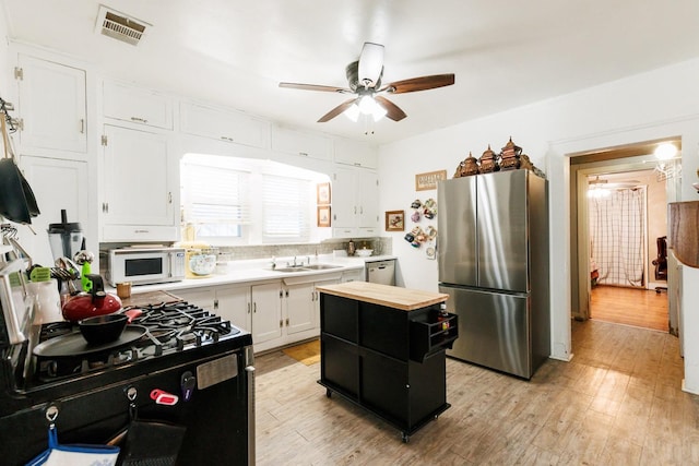 kitchen with sink, light wood-type flooring, appliances with stainless steel finishes, ceiling fan, and white cabinets