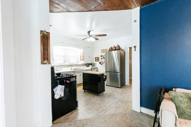 kitchen with sink, stainless steel refrigerator, range, white cabinetry, and a center island