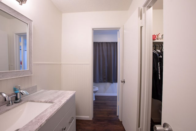 5426 9th St, Lubbock, TX 79416 - bathroom featuring wood finished floors, vanity, wainscoting, and a spacious closet