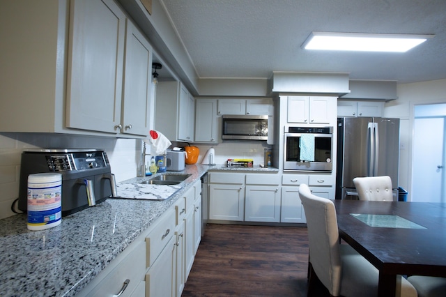 5426 9th St, Lubbock, TX 79416 - kitchen featuring stainless steel appliances, dark wood finished floors, light stone counters, and backsplash