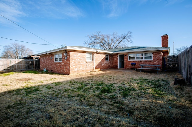 5426 9th St, Lubbock, TX 79416 - rear view of house with a chimney, a fenced backyard, and brick siding