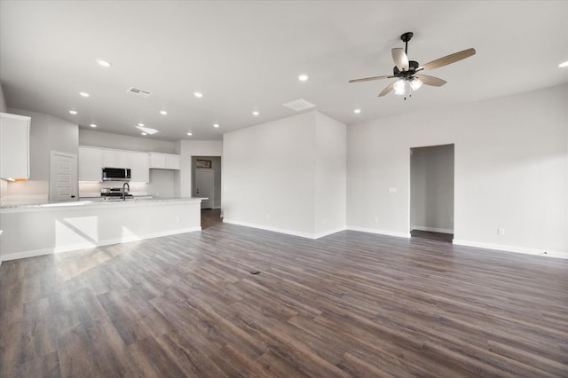 unfurnished living room with dark wood-type flooring, ceiling fan, and sink