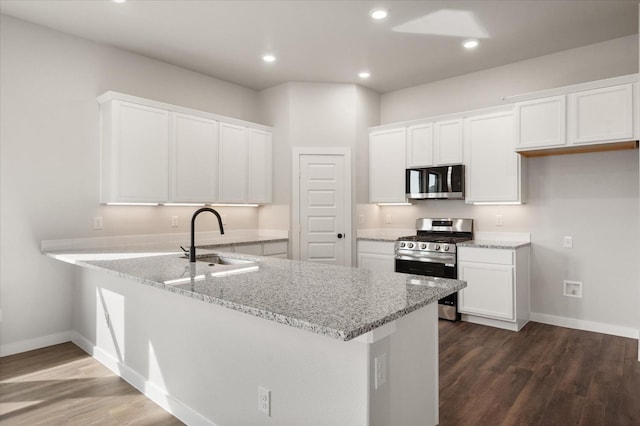 kitchen featuring stainless steel appliances, kitchen peninsula, sink, and white cabinets