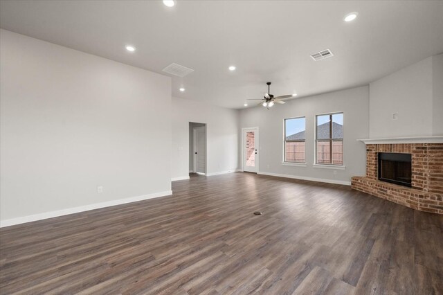 unfurnished living room featuring a fireplace, dark hardwood / wood-style floors, and ceiling fan