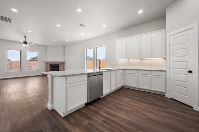 kitchen featuring sink, dark wood-type flooring, dishwasher, white cabinetry, and a fireplace