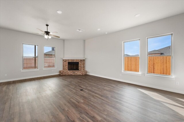 unfurnished living room with dark hardwood / wood-style flooring, a brick fireplace, and ceiling fan