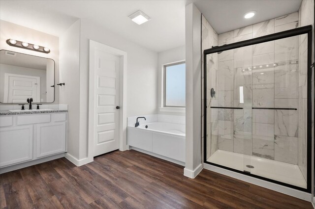 bathroom featuring vanity, wood-type flooring, and plus walk in shower